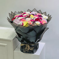 Bouquet of flowers wrapped in black paper on a white surface with a light gray background