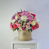 Luxury flower arrangement in a round box with mixed pastel roses and chrysanthemums