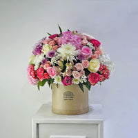 Luxury flower arrangement in a round box with mixed pastel roses and chrysanthemums