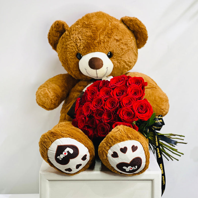 Brown teddy bear holding a bouquet of red roses best gift for your loved once in doha qatar, order online for same day delivery.