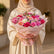 Bouquet of flowers wrapped in pink paper with gold accents on a white surface.