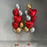 Two clusters of metallic foil balloons, one red and one gold, mixed with silver and gold balloons, standing on a tiled floor against a gray wall.