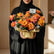 Bouquet of orange and pink roses with a decorative card on a white surface.