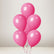 Five glossy pink balloons clustered together with thin pink strings, photographed against a soft light gray studio background.