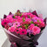A vibrant bouquet of pink flowers, including roses, gerbera daisies, and purple alstroemeria, wrapped in dark purple paper with a small card at the top.