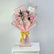 A bouquet of pink roses wrapped in light pink paper with gold trim and tied with a gold ribbon, displayed on a white pedestal against a light gray background.