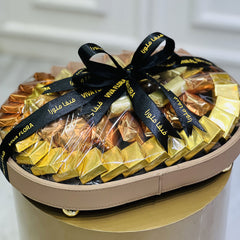 oval shaped box of gold and orange wrapped premium with black ribbons on a white background