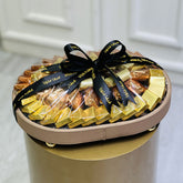 Ovel shape tray of chocolates with a black ribbon on a white background