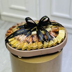 Ovel shape tray of chocolates with a black ribbon on a white background