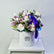 A floral arrangement of white and light purple roses with green foliage, presented in a round white box with the brand name VIVA FLORA, tied with a purple ribbon, set on a white pedestal against a light gray background.