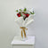 A bouquet of red roses mixed with white baby's breath and green eucalyptus stems, wrapped in white paper with a gold ribbon, displayed on a white pedestal against a light gray background.