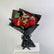 A bouquet of red roses wrapped in black paper with green leaves and white baby's breath, tied with a black ribbon, displayed on a white pedestal against a light gray background.