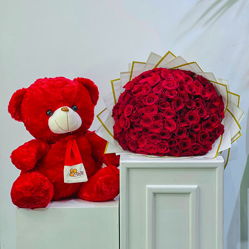 Red teddy bear 60cm next to a bouquet of red roses on a white surface. perfect for this valentines, anniversary and birthday 