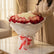 A large bouquet of roses wrapped in white tissue paper and tied with a red and white ribbon, displayed on a white pedestal against a plain light gray background.