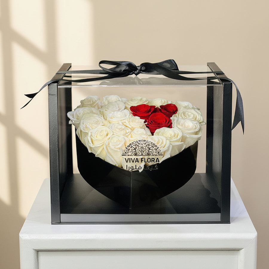 Heart-shaped arrangement of white and red roses in a clear box with a black ribbon, branded 'VIVA FLORA QATAR' send flowers to qatar online .