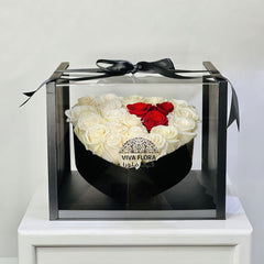 Heart-shaped arrangement of white and red roses in a clear box with a black ribbon, branded 'VIVA FLORA QATAR' send flowers to qatar online .