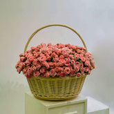 Basket filled with soft pink spray roses arranged in a rounded floral display