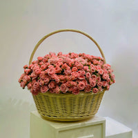 Basket filled with soft pink spray roses arranged in a rounded floral display