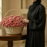 Basket of pink roses on a white pedestal against a white background