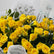 A dense bouquet of bright yellow roses with green leaves, arranged with printed cards and a small gold paperclip in the background.