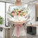 A woman in a beige blazer holds a large, beautifully wrapped flower bouquet in a bright, modern office setting. The bouquet features a mix of peach, pink, white, and burgundy roses with green foliage, wrapped in white paper with a soft pink ribbon.